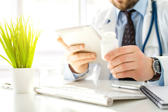 Doctor uses the tablet while sitting in his office