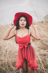 Portrait of asian beautiful woman in red dress with red hat at the field,alone,sad woman,heartbreak girl,vintage style