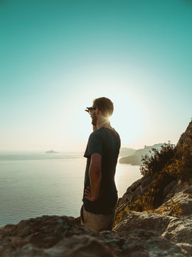 Young Man Standing on top of a Cliff