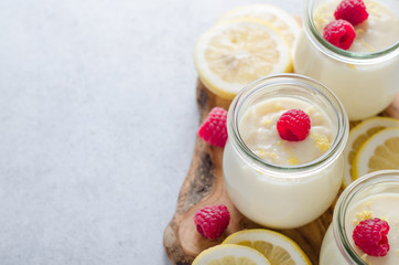 Lemon or vanilla curd in glass jars with raspberry and lemon sli