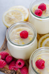 Lemon or vanilla curd in glass jars with raspberry and lemon sli