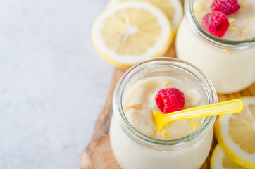 Lemon or vanilla curd in glass jars with raspberry and lemon sli