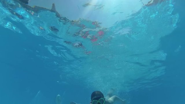 girl in mask finding camera underwater, smiling