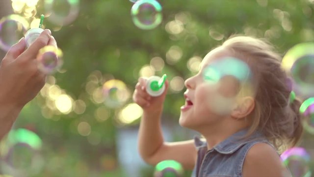 Beautiful mother and her little daughter having fun in summer park together. Slow motion 4K UHD video 3840X2160