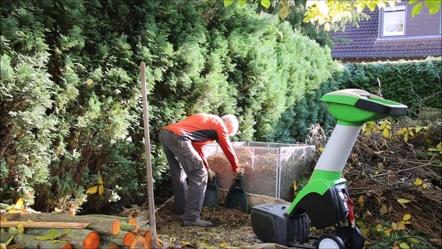 Herbst-Arbeitsplatz im Garten mit H&auml;cksler und Komposthaufen