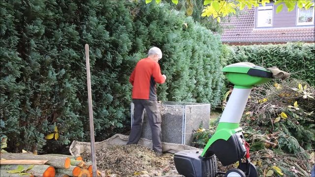 Herbst-Arbeitsplatz im Garten mit H&auml;cksler und Komposthaufen