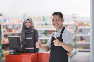 male shopkeeper showing thumb up - Powered by Adobe