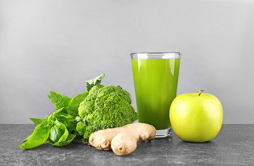 Green juice in glass with ingredients on table