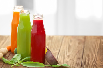 Bottles with various fresh vegetable juices and ingredients on table