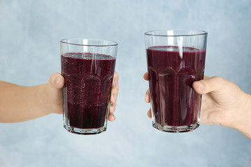 Women holding glasses with acai juice on light background