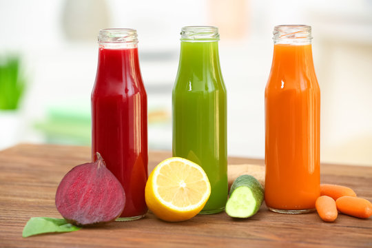 Bottles with various fresh vegetable juices and ingredients on table