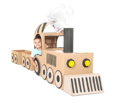 Little boy playing with cardboard train on white background