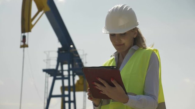 Portrait of engineering female coordinator supervising petroleum installation satisfied by her successful work using tablet pc