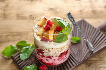 Oatmeal dessert with yogurt, raspberries and peaches in glass on table