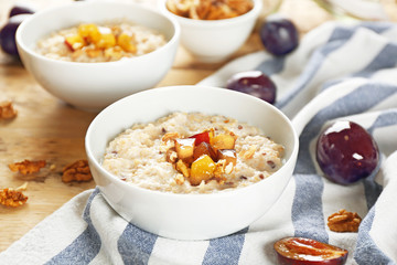 Delicious oatmeal porridge with fruit in bowl on table