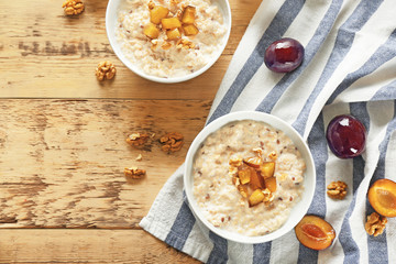 Delicious oatmeal porridge with fruit in bowls on table