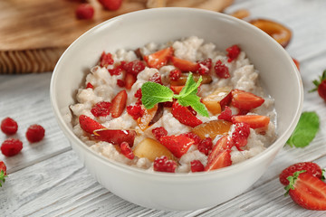 Delicious oatmeal porridge with fruits in bowl on table