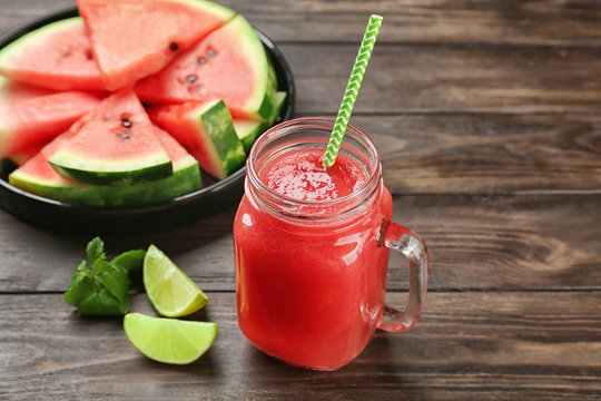 Mason jar with fresh watermelon smoothie on wooden table
