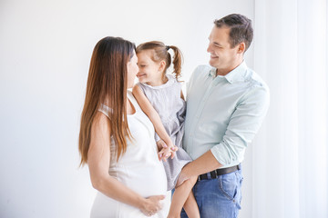 Happy young family against white wall