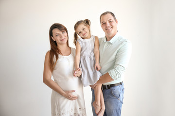 Happy young family against white wall