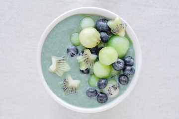 Blue spirulina smoothie bowl with melon, kiwi fruit and blueberries