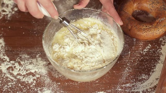 Cook whips the dough in a glass plate, close-up. Slow motion.