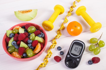 Fruit salad, glucometer, centimeter and dumbbells, diabetes, healthy lifestyle and nutrition concept