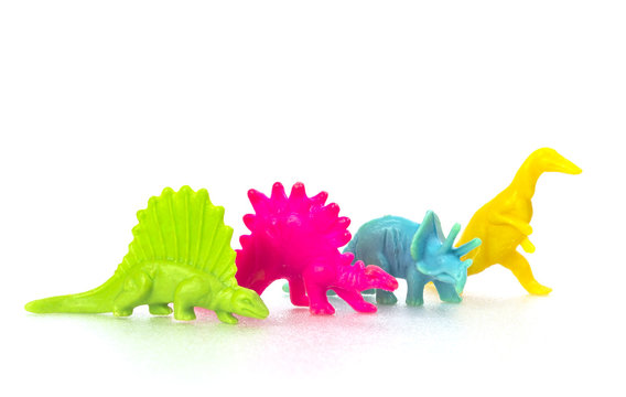 Small colorful dinosaur toy on white background in a row