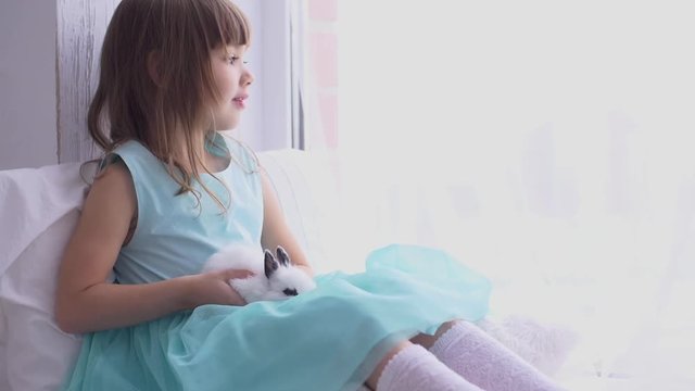 Pretty teen girl having fun, hugging and playing with decorative rabbit