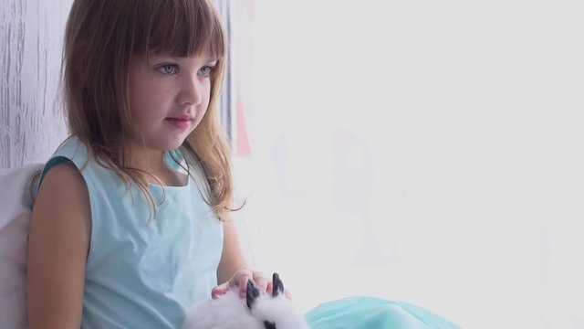 Pretty teen girl having fun, hugging and playing with decorative rabbit
