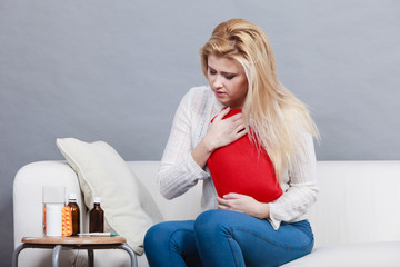 Woman feeling stomach cramps sitting on cofa