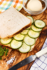preparing a white toast sandwich with organic cucumber