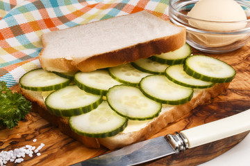 preparing a white toast sandwich with organic cucumber