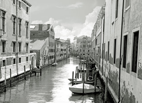 Black and white of small venetian canal and old brick walls with vintage traditional balconies. Venice, Italy