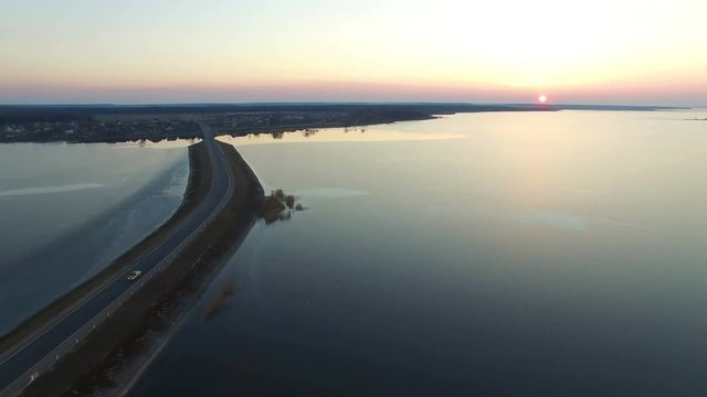 4K. Flight over road in the frozen water in winter on sunset, aerial view.