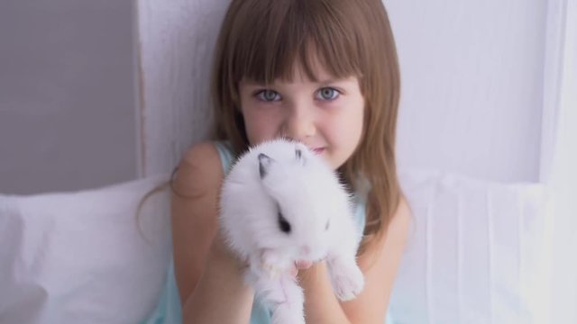 Pretty teen girl having fun, hugging and playing with decorative rabbit