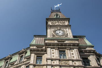 Fototapeta na wymiar Classic clocktower building Quebec City Canada with flag of quebec on a sunny day blue sky