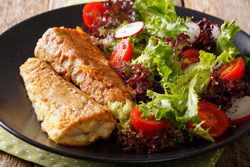 Healthy lunch: fried hake with tomato, radish and lettuce salad close-up. horizontal
