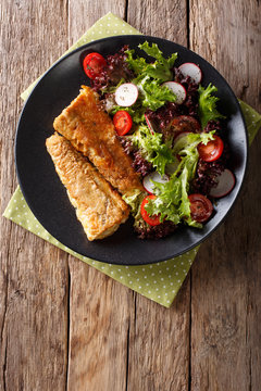 fried in a battered hake and fresh salad close-up. Vertical top view