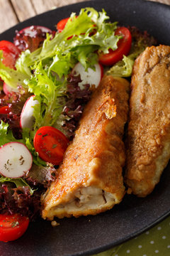 fried in a battered hake and fresh salad close-up. vertical