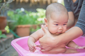 Closeup asian baby  take a shower on daylight in pink Basin