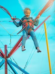 Fototapeten Girl tied by red seat belts goes up on the attraction. © kvladimirv