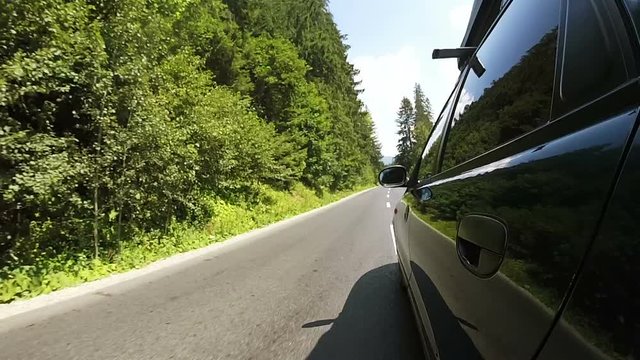  Green Car goes on  good  road  in rural area with wood