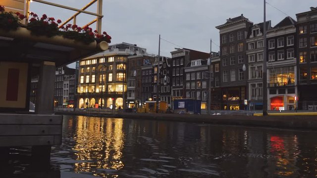 Sailing in the waters of the Rokin canal in Amsterdam and looking at the street architecture in the background at dusk.