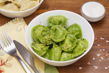 Meat dumplings - russian pelmeni, ravioli with meat on a white plate on a wooden background