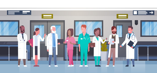Obraz premium Group Of Doctors In Hospital Corridor Diverse Medical Workes In Modern Clinic Flat Vector Illustration