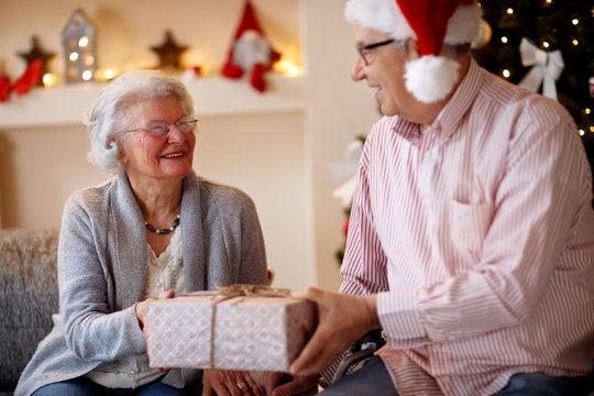 beautiful elderly couple celebrating Christmas at home with presents  .