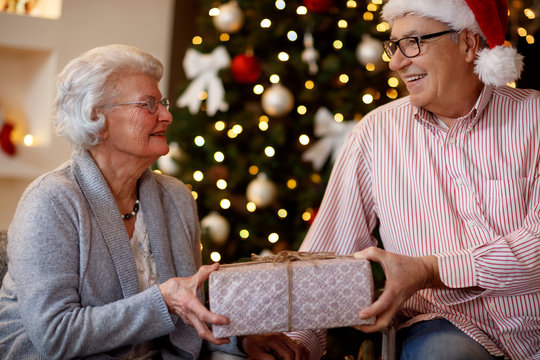 family, holidays, age and people concept - smiling senior couple with Christmas gift.