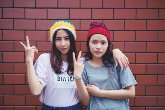 Portrait asian hipster girls on brick wall background,Hippie dress style,Thailand modern woman lifestyle,Beauty fashion portrait outdoor
