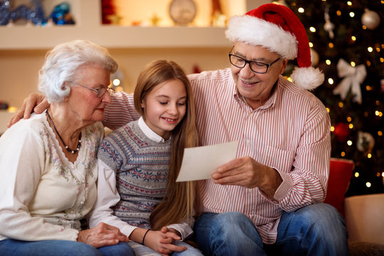 smiling grandparents with granddaughter watching photo and share memory on Christmas.